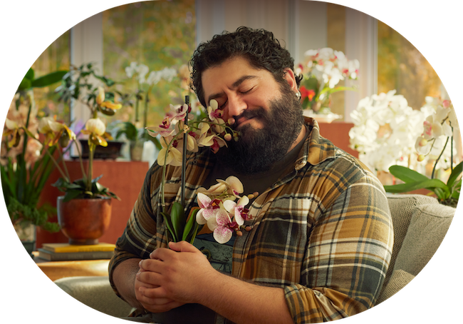 A man hugging a plant and smiling. He seems very happy and content.